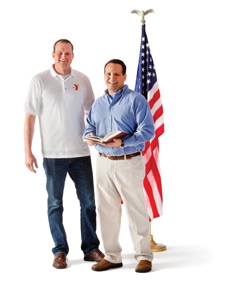 Two men standing in front of American flag.
