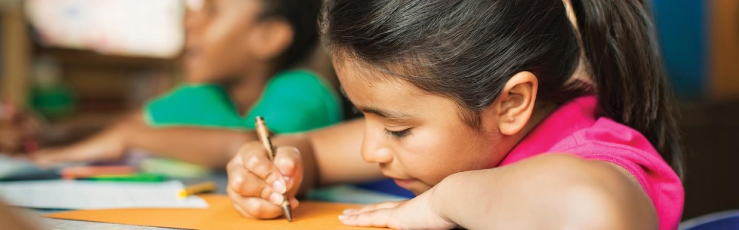 Girl coloring with crayon at desk
