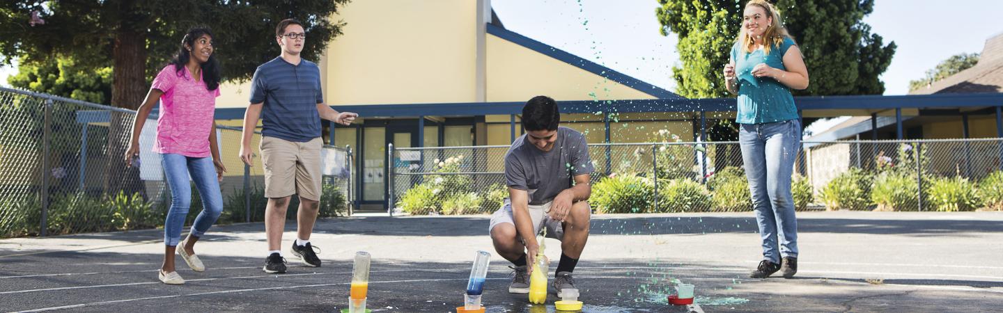 Teens performing science experiment outside.