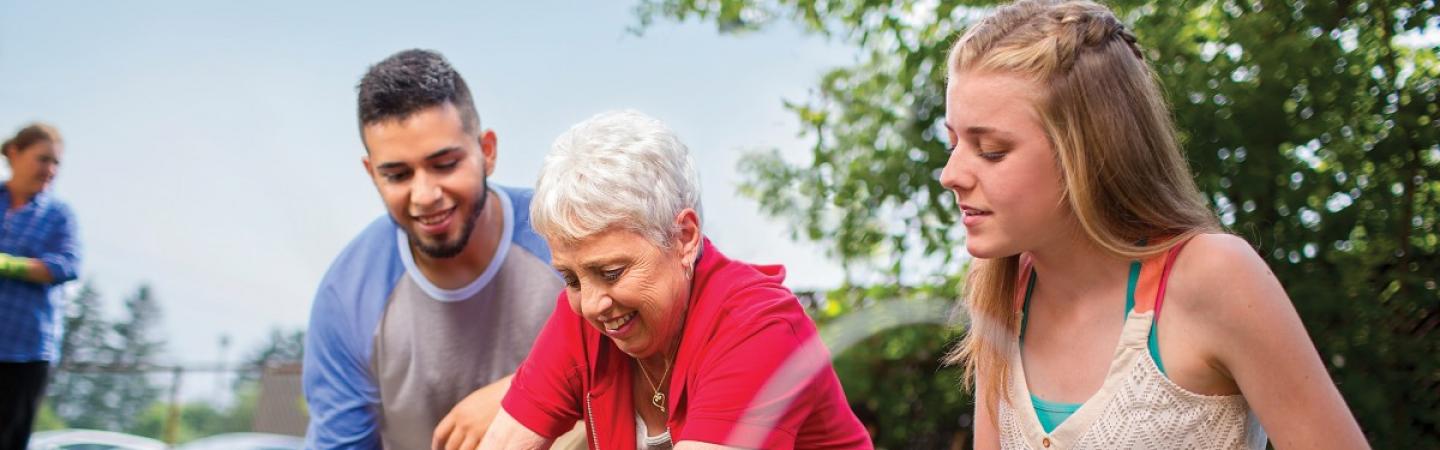 Two teenagers volunteering their time to help an elderly person in their community.