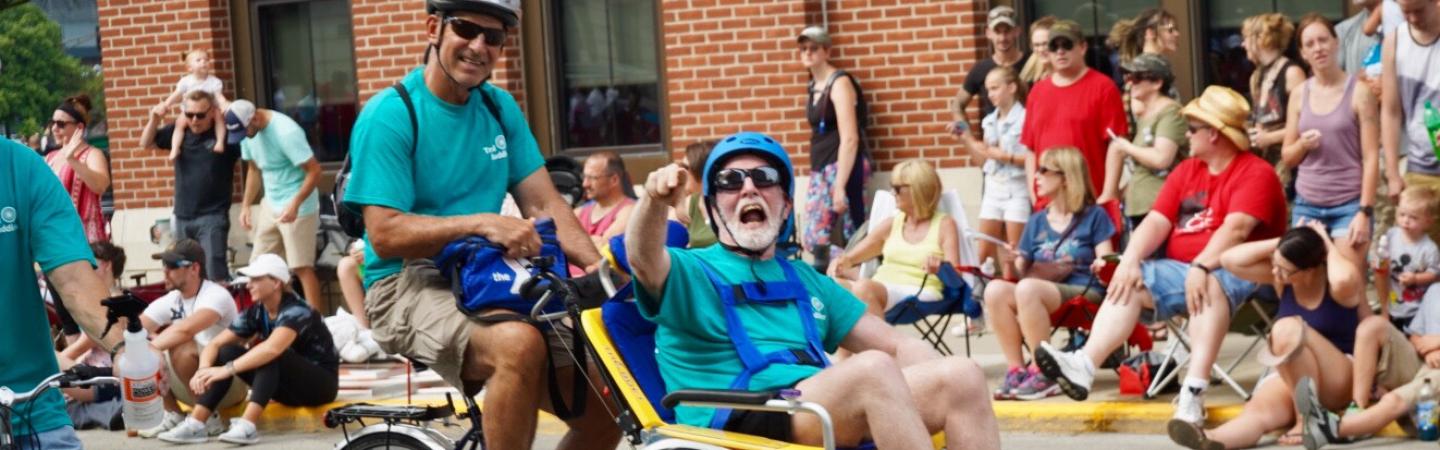 Two men riding on the duet bike for the YMCA of Greater Fort Wayne in the three rivers parade.