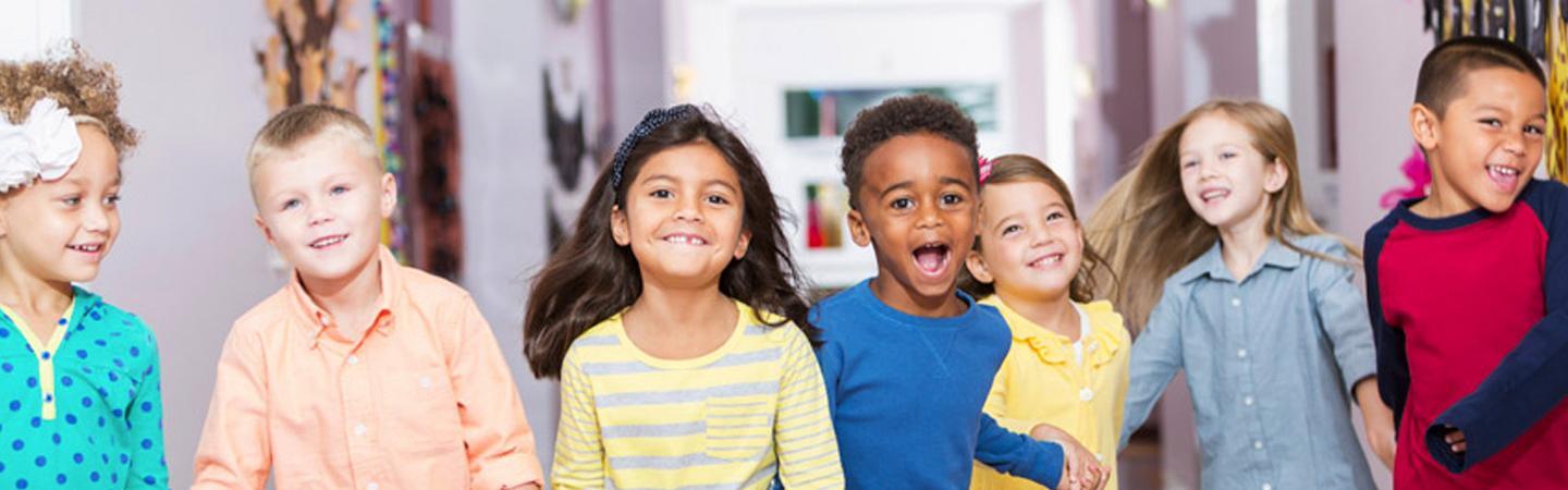 Seven children at a YMCA childcare holding hands and having fun.