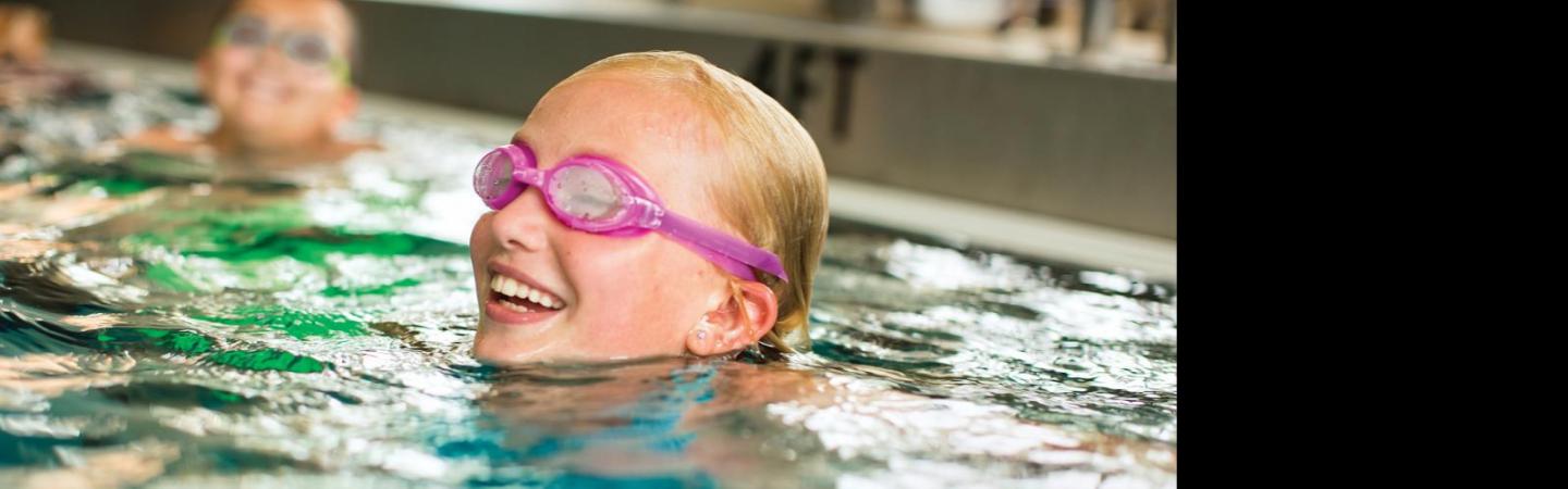 Girl with goggles on swimming in a pool.