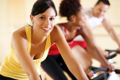 Three adults on stationary exercise bikes.