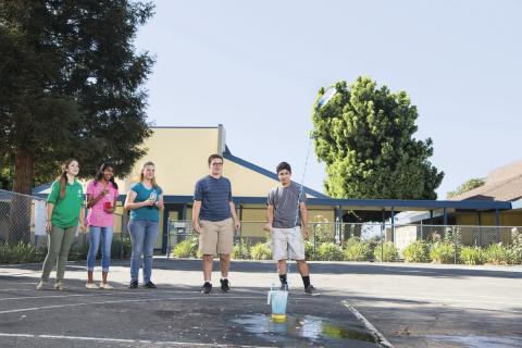 Four teenagers watching water rocket launch.